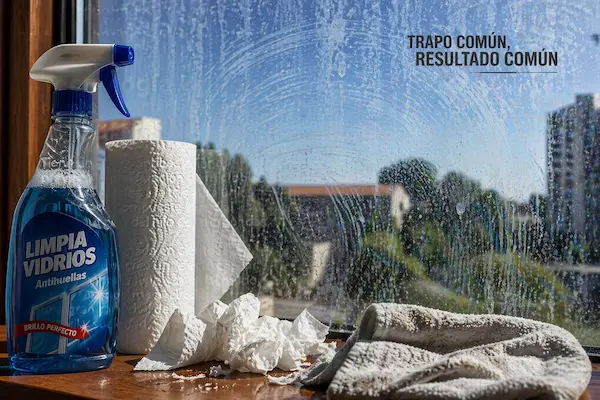 Vidrio con vetas limpiado con papel, limpiavidrios y trapo común